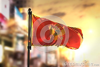 Montenegro Flag Against City Blurred Background At Sunrise Backlight Stock Photo