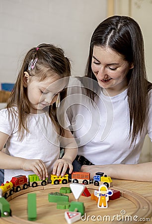 Montessori material. Mom and daughter learn transport through the game. Wooden railroad Stock Photo