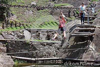 Montestrutto, Italian alps - June 2020: a girl throws herself into a rope-smeared cliff in an adventure park Editorial Stock Photo