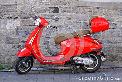 Montreal, Canada - October 27, 2019 - A bright red Vespa scooter parked on the brick street Editorial Stock Photo