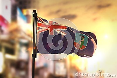 Montserrat Flag Against City Blurred Background At Sunrise Backlight Stock Photo