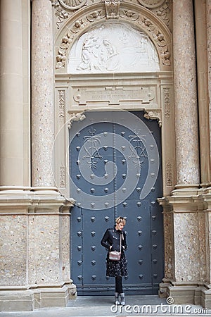 Montserrat, Spain - April 5, 2019: Young wonan poses in front of the Santa Maria de Montserrat Abbey, Catalonia, Spain. Editorial Stock Photo