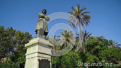Monument of man on pedestal on background of green trees and sky. Action. Bottom view of beautiful statue of man on Editorial Stock Photo