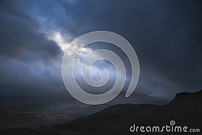 Moody and dramatic Winter landscape image of Moel Saibod from Crimpiau in Snowdonia with stunning shafts of light in stormy Stock Photo