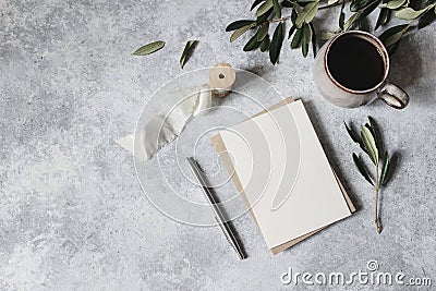 Moody feminine wedding stationery mock-up scene. Blank greeting card, cup of coffee, silver pen with olive leaves Stock Photo