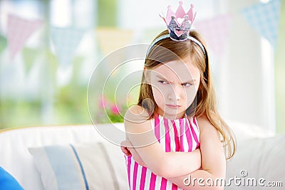 Moody little girl wearing princess tiara feeling angry and unsatisfied Stock Photo