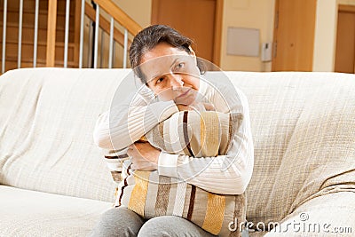 Moody senior woman sitting on sofa Stock Photo