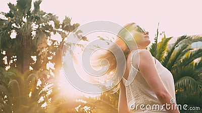 Mooie modieuze blonde vrouw in zonnebril, die langs een palmweg lopen De palm wordt weerspiegeld in de glazen 4K stock footage Mooie modieuze blonde vrouw in zonnebril, die langs een palmweg lopen De palm wordt weerspiegeld in de glazen 4K stock footage