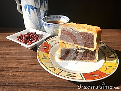 Moon cake stack together, served with tea, and some red beans in sauce dish at side, on wooden background. Stock Photo