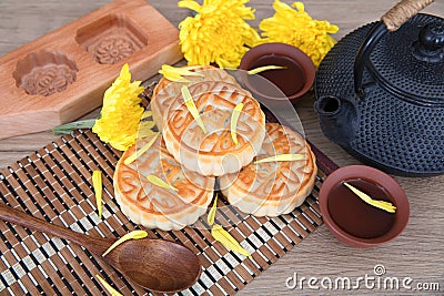 Moon cakes and a pot of tea and moon cake molds and golden chrysanthemums placed on the table.Chinese characters on the moon cake Stock Photo