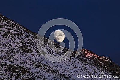 Moon over snowy mountain in Switzerland Stock Photo