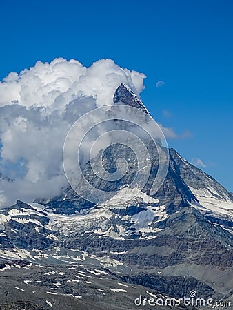 Moon shining over the famous matterhorn with clouds and blue sky Stock Photo