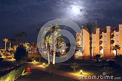 Moonlight illuminating tropical resort with hotel building and palm trees at night Editorial Stock Photo