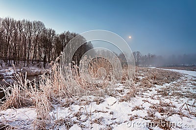 Moonlight in the winter dawn. Fog and mist on snowy winter river Stock Photo