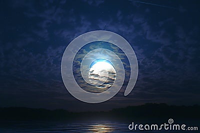 Moonlit sky over tranquil sea, with clouds adding mystical beauty Stock Photo