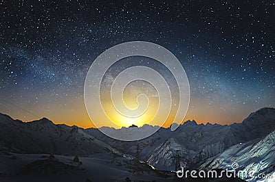 Moonset in the mountains at night with a horizontal milky way on the sky. Snow covered peaks of mountains at night Stock Photo