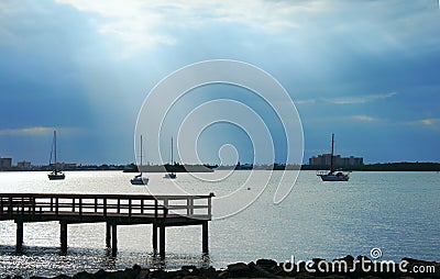 Moored sailboats in calm bay with dramatic clouds sun rays Stock Photo