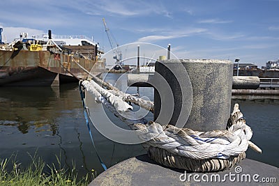 Mooring bollard with ship ropes. Bollard with mooring ropes on the quay. Moored ship at the port quay Stock Photo