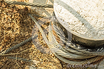 Mooring part of the port equipment coarse twisted rope iron rusty weathered close-up fixed on the cement block Stock Photo