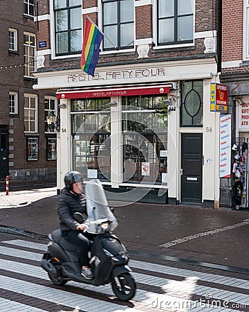Moped rider driving past a gay bar on Amstel street in Amsterdam Editorial Stock Photo