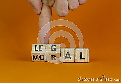 Moral or legal symbol. Businessman hand turns wooden cubes and changes the word `moral` to `legal` on a beautiful orange table Stock Photo