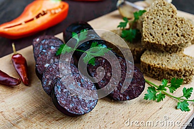 Morcillo Spanish black pudding, blood sausage, cutting slices, black rye bread in a heart shape, pepper, garlic Stock Photo