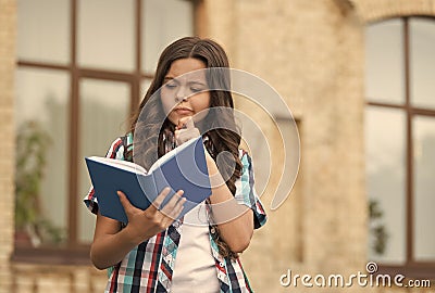 The more you read, the more you learn. Serious child read book outdoors. School library. Literacy education. Reading Stock Photo