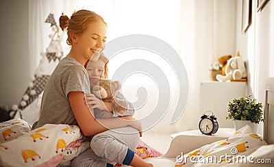 Mother wakes her daughter in bed in morning Stock Photo