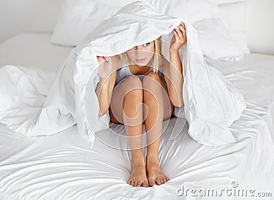 Morning, bed and woman hide with blanket for fear or anxiety in home and sheet to cover body. Nervous, girl and duvet Stock Photo