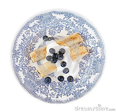 Morning breakfast with french crepes, fresh blueberry, yogurt on a plate isolated on white background. Stock Photo