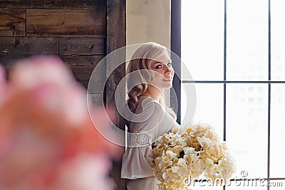 Morning of the bride. A gorgeous bride, a beautiful woman with long hair in a white robe by the window. The bride before the Stock Photo