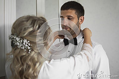 Morning of the bride and groom. the bride helps to dress the groom on the wedding day. selective focus. Stock Photo