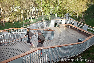 Morning cardio. Sporty african couple in black sportswear running up stairs in park. Full length. Dark-skinned man and Stock Photo