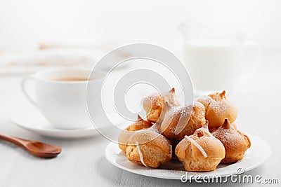 Morning coffee with cakes. Profiteroles, coffee, cream on a white wooden table Stock Photo