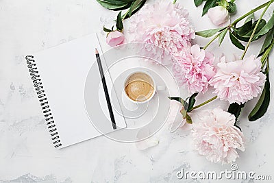 Morning coffee mug for breakfast, empty notebook, pencil and pink peony flowers on white stone table top view in flat lay style. Stock Photo