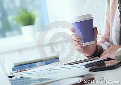 Morning coffee before a productive working day. Young female office worker holding coffee papercup and looking at the Stock Photo