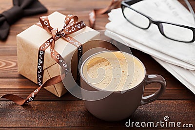 Morning cup of coffee, gift, newspaper, glasses and bowtie on wooden desk for breakfast on Happy Fathers Day Stock Photo