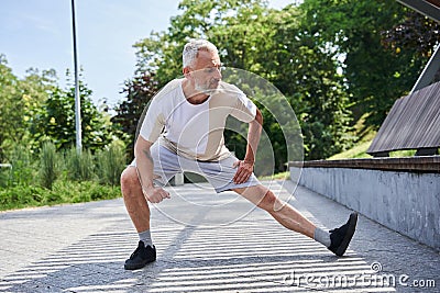 Mature man stretching body and feeling flexible while exercising at the park Stock Photo