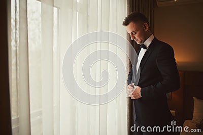 Morning of the groom before the wedding. Groom morning preparation. Young and handsome groom getting dressed in a wedding suit Stock Photo