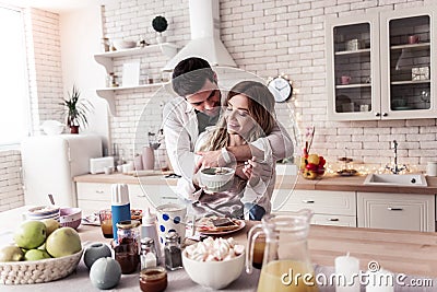 Pretty long-haired young woman in a white shirt and her husband standing in the kitchen Stock Photo