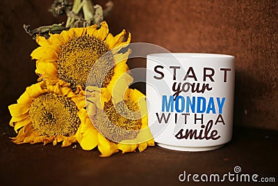 Morning inspirational words on white mug of coffee - Start your Monday with a smile. With sunflowers blossom arrangement. Stock Photo