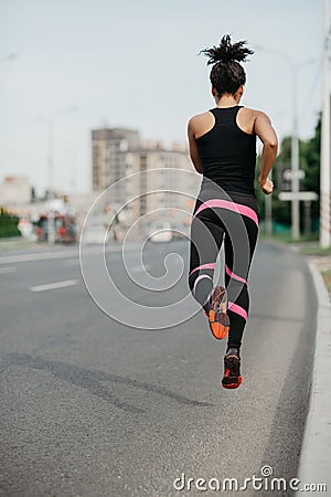 Morning jog on road in city. Muscular girl in sportswear froze in air, jogging Stock Photo