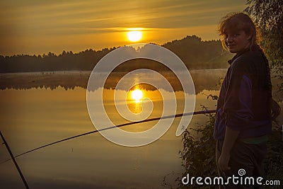 Morning on the lake dawn. A fisherman is standing on the shore next to fishing rods Stock Photo