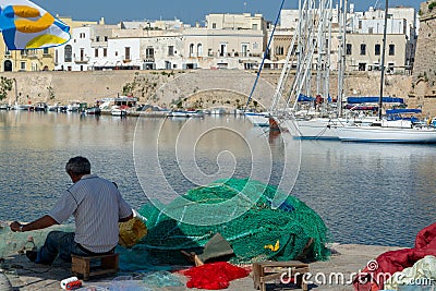 Morning landscape photo made in Gallipoli pier, fishermen reparing his fishermen net after fishing, Apulia, Italy Editorial Stock Photo