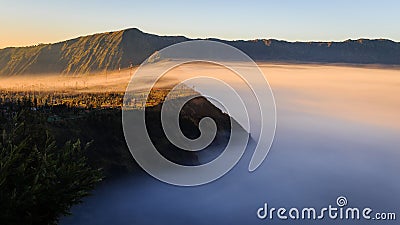 Morning Mist covers Cliff Village in Mount Bromo, Indonesia Stock Photo