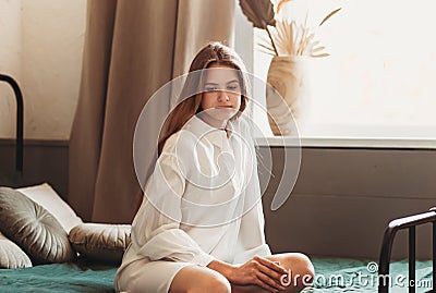 Morning portrait of a brooding young girl with long hair on a bed in the bedroom Stock Photo