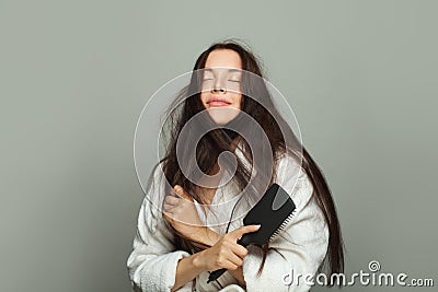 Morning routine. Cute woman combing her tangled hair on white background Stock Photo