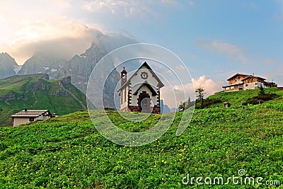 Morning scenery of a lovely church at the foothills of rugged mountain peaks Cimon della Pala Stock Photo