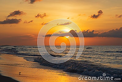 The morning sun breaks through a cloud bank and reflects off the receding water. Stock Photo