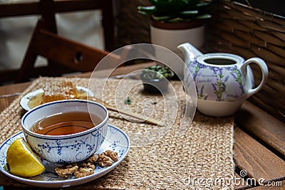 Morning tea time, cup of natural tea, teapot, organic honey, fresh green tea leaves and organic fruits Editorial Stock Photo